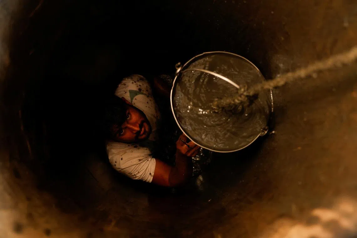 FILE PHOTO: A man cleans out a small well in Chandrapur, India, February 3, 2025. REUTERS/Priyanshu Singh/File Photo