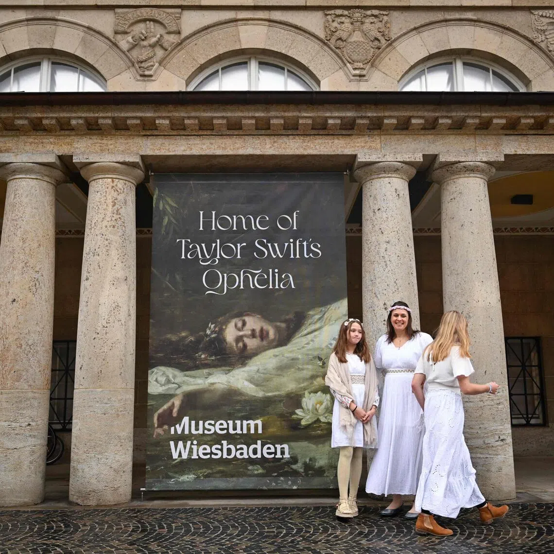 Fans of US singer-songwriter Taylor Swift pose next to a placard with the title 'Home of Taylor Swift's Ophelia' outside the Museum in Wiesbaden, western Germany, on Nov 2. 