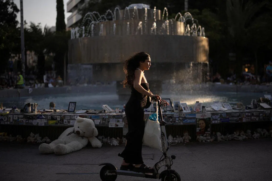 A woman on a scooter passes by pictures and memorabilia of hostages kidnapped during the deadly Oct 7 attack by the Palestinian Islamist group Hamas, in Tel Aviv on June 2.    