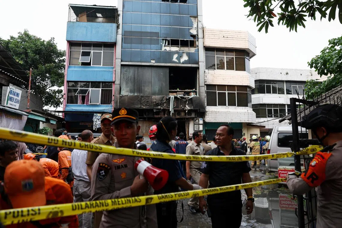 Police officers stand near a seven-storey building damaged by fire, in Jakarta, Indonesia, on Dec 9. 
