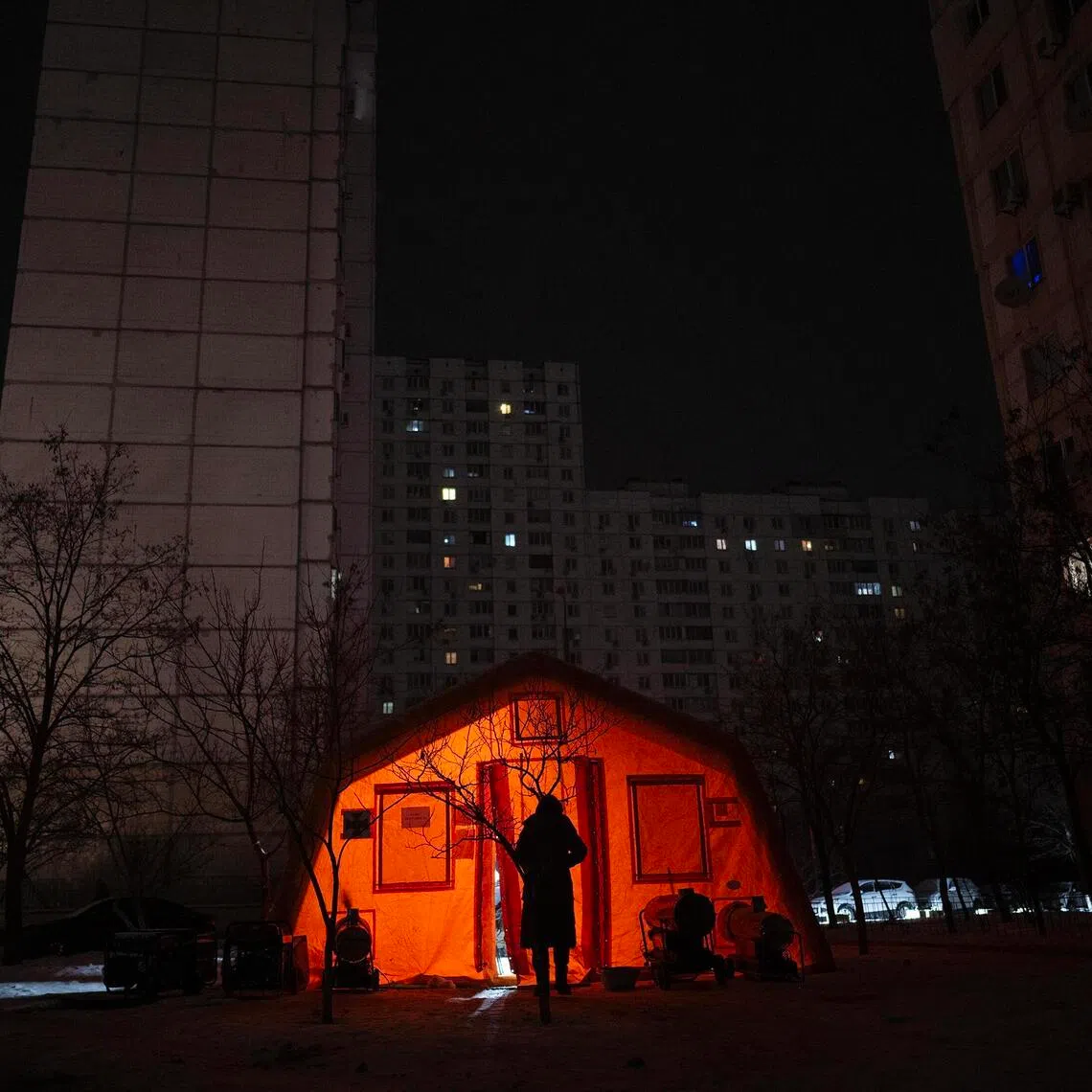 A resident entering a tent set up to offer electricity and heat on Jan 13, in Kyiv, Ukraine, due to power outages caused by Russian air strikes.