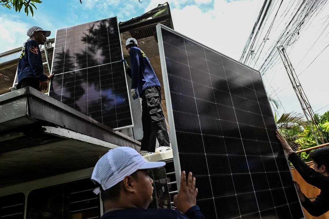Image 1: Workers carry solar panels to be installed on the roof of a house in Kawit, Philippines, . REUTERS/Noel Celis