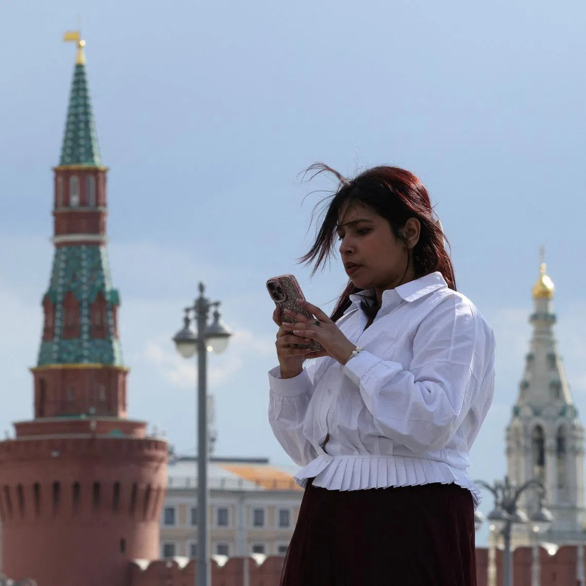 A woman checks her mobile phone near the Kremlin wall in central Moscow, Russia, May 4, 2026. REUTERS/Ramil Sitdikov