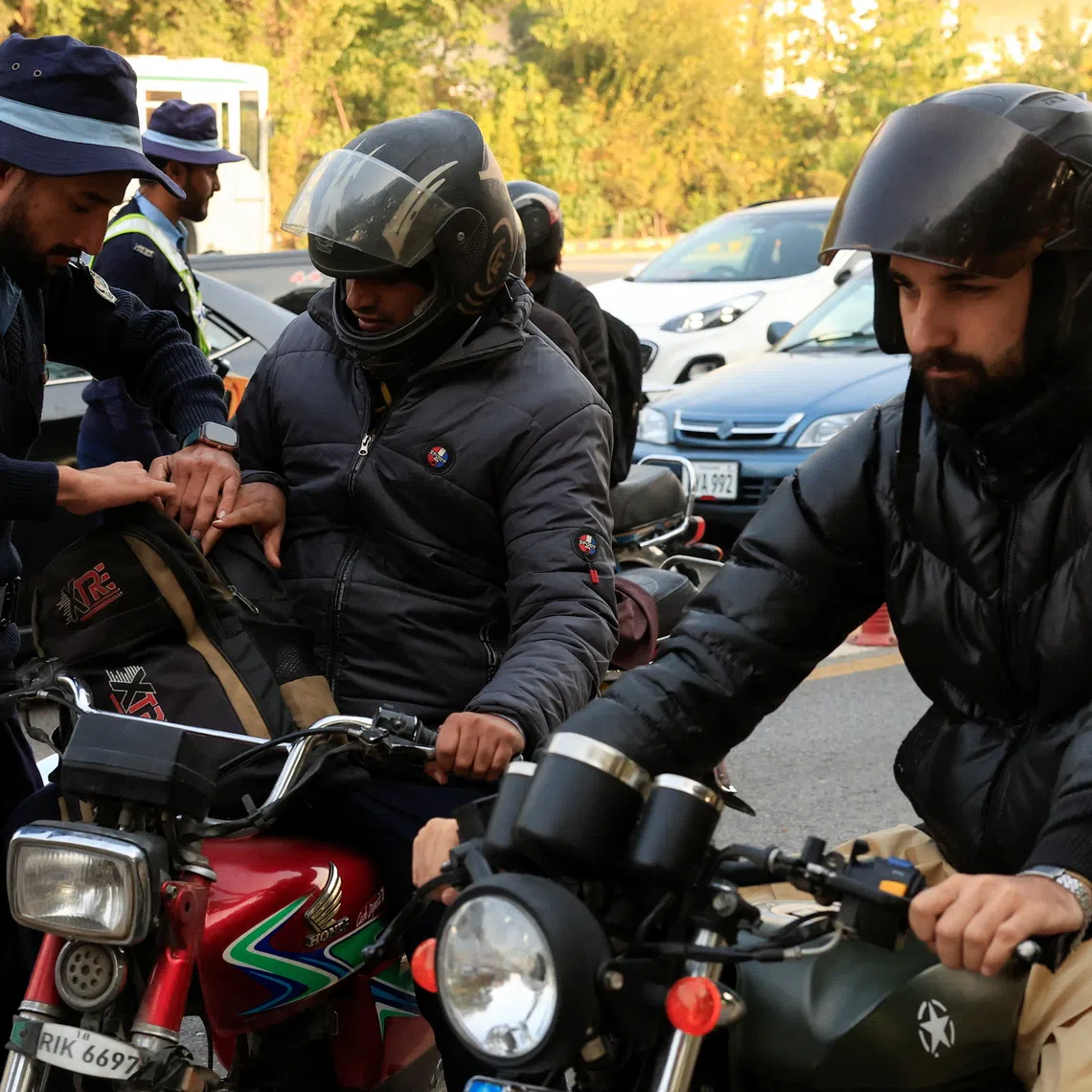 A police officer checks the bag of a biker at a security check post along a road following yesterday's blast outside the district court building, in Islamabad, Pakistan, November 12, 2025. REUTERS/Akhtar Soomro