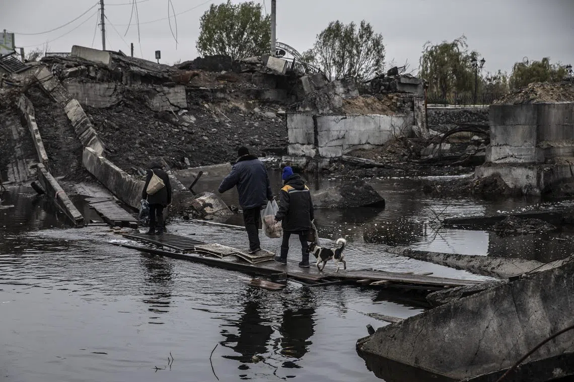 Civilians cross the remains of a bridge that was destroyed by Russian bombardment in Bakhmut, a heavily-contested city in Ukraine’s Donetsk region. 