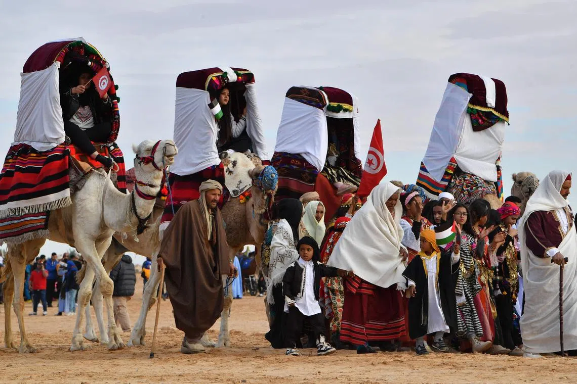 Performers wearing traditional outfits riding camels during a show at the start of the  55th International Sahara Festival on Dec 27, 2023 in Douz, in southern Tunisia. 