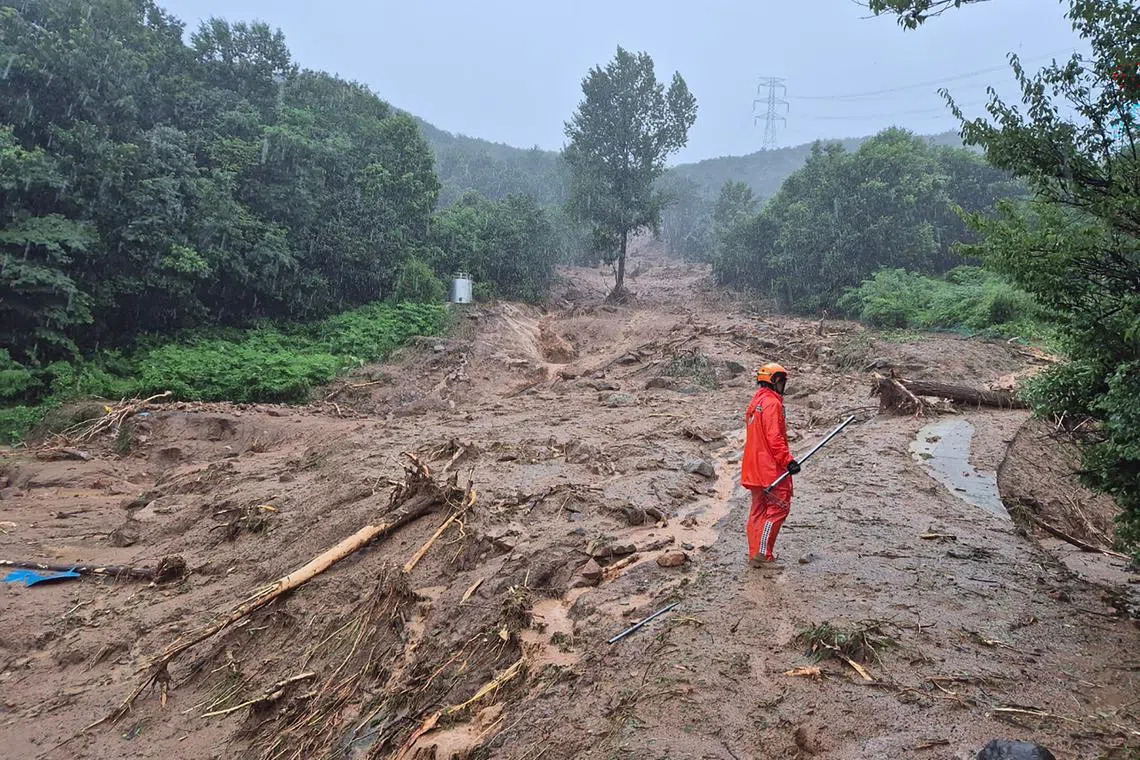 A rescue member standing on a mud-covered road after a landslide hit a village in southern Sancheong county in South Korea on July 19.