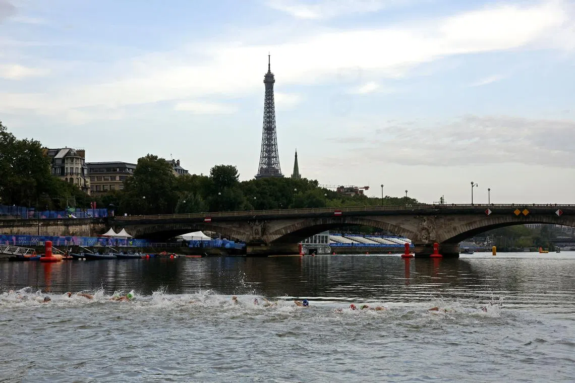 Paris 2024 Olympics - Triathlon - Women's Individual - Alexander III Bridge, Paris, France - July 31, 2024. Athletes swims in the river Seine at the start of the race as the Eiffel Tower is seen. REUTERS/Lisa Leutner