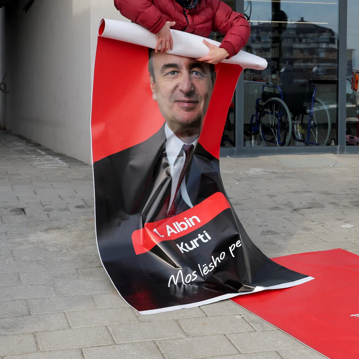 A worker holds an election campaign poster with a portrait of acting Prime Minister of Kosovo and Levizja Vetevendosje (Movement for Self-Determination) party leader Albin Kurti, in Pristina, Kosovo December 16, 2025. Kosovo is to hold a snap parliamentary election on December 28, nearly a year after a political deadlock that prevented the formation of a new government. REUTERS/Valdrin Xhemaj/File Photo