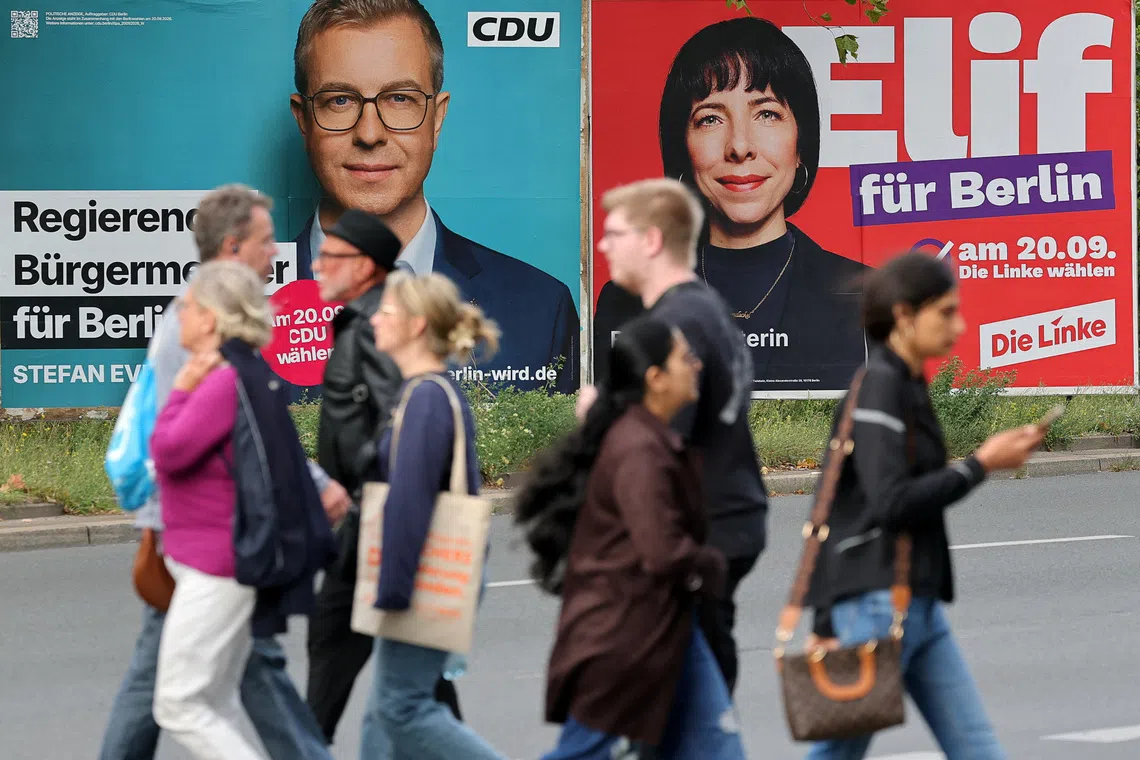 People walk near election signs for Christian Democratic Union (CDU) top candidate Stefan Evers and Die Linke (the Left) top candidate Elif Eralp on Sept 19, ahead of state elections in Berlin, Germany.