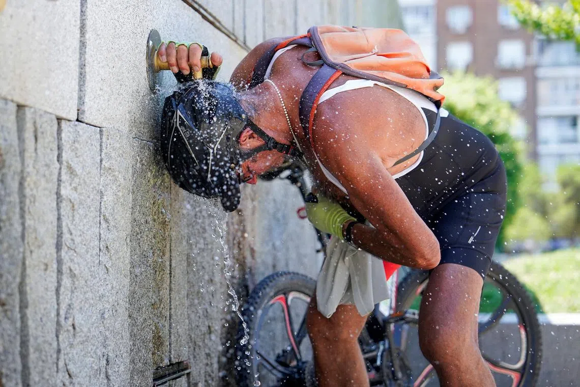 A cyclist cools off at a fountain at Madrid Rio park during the second day of the heatwave, in Madrid, Spain, July 25, 2024. REUTERS/Ana Beltran