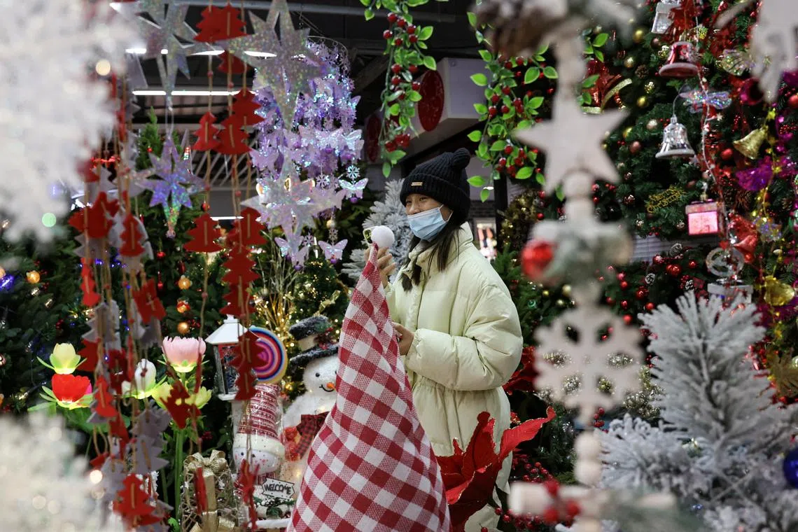 A customer shops at a booth selling Christmas decorations at a mall in Beijing on December 14, 2023. 