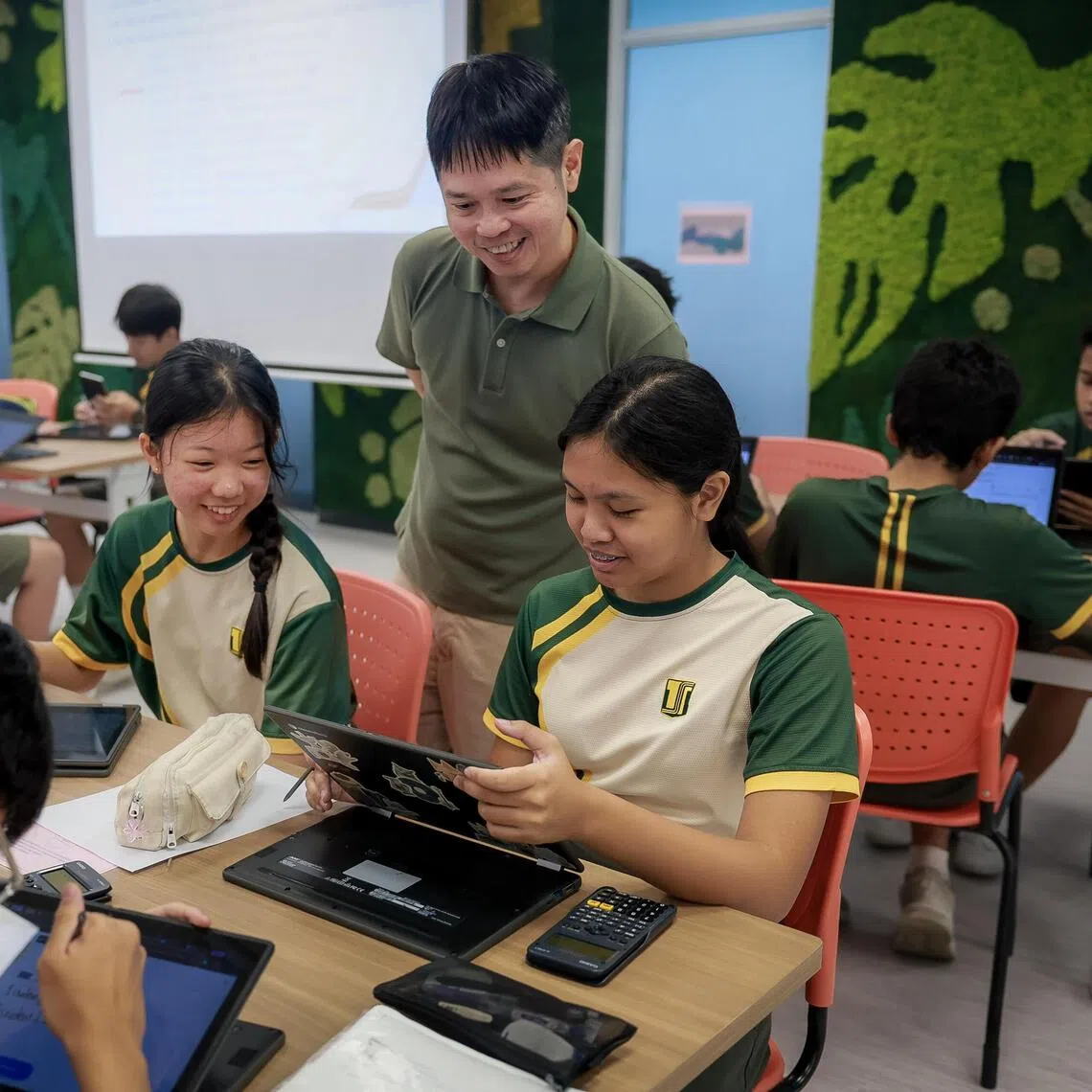 Tampines Secondary maths teacher Charles Yip guiding Sec 2 students (clockwise from bottom left) Alexis Koh, Reiko Toh and Raina Mahani as they use AI-powered learning tools.