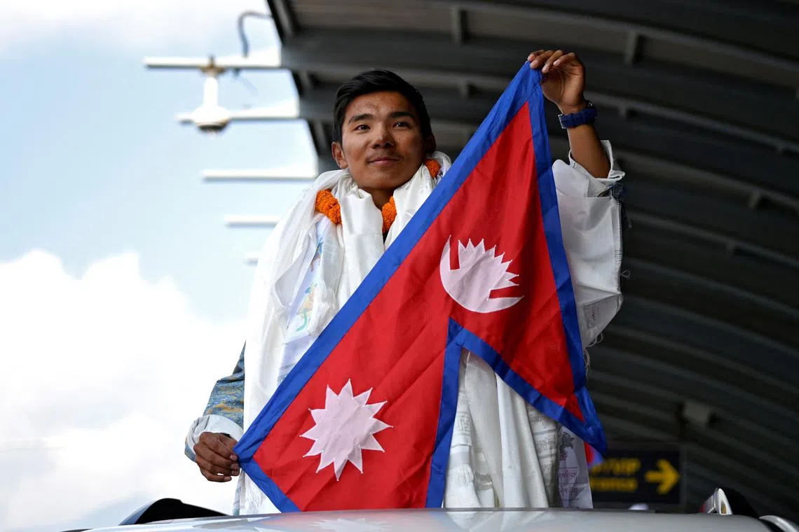 Nima Rinji Sherpa, who claims the record for youngest person to scale world's 14 highest peaks, holds a national flag upon his arrival at the airport during a welcoming ceremony in Kathmandu, Nepal, October 14, 2024. REUTERS/Monika Malla/File Photo