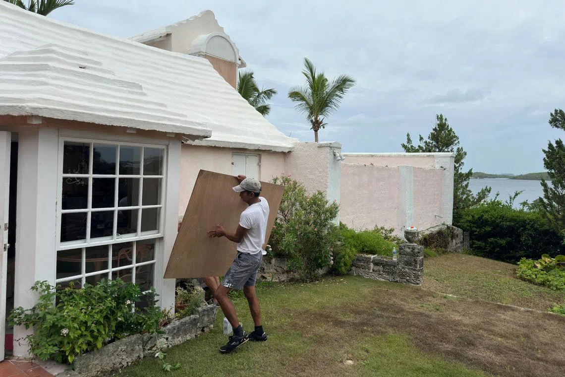 A man boards up a house to protect it from the approaching Hurricane Ernesto in Warwick, Bermuda August 16, 2024.  REUTERS/Mary F. Calvert