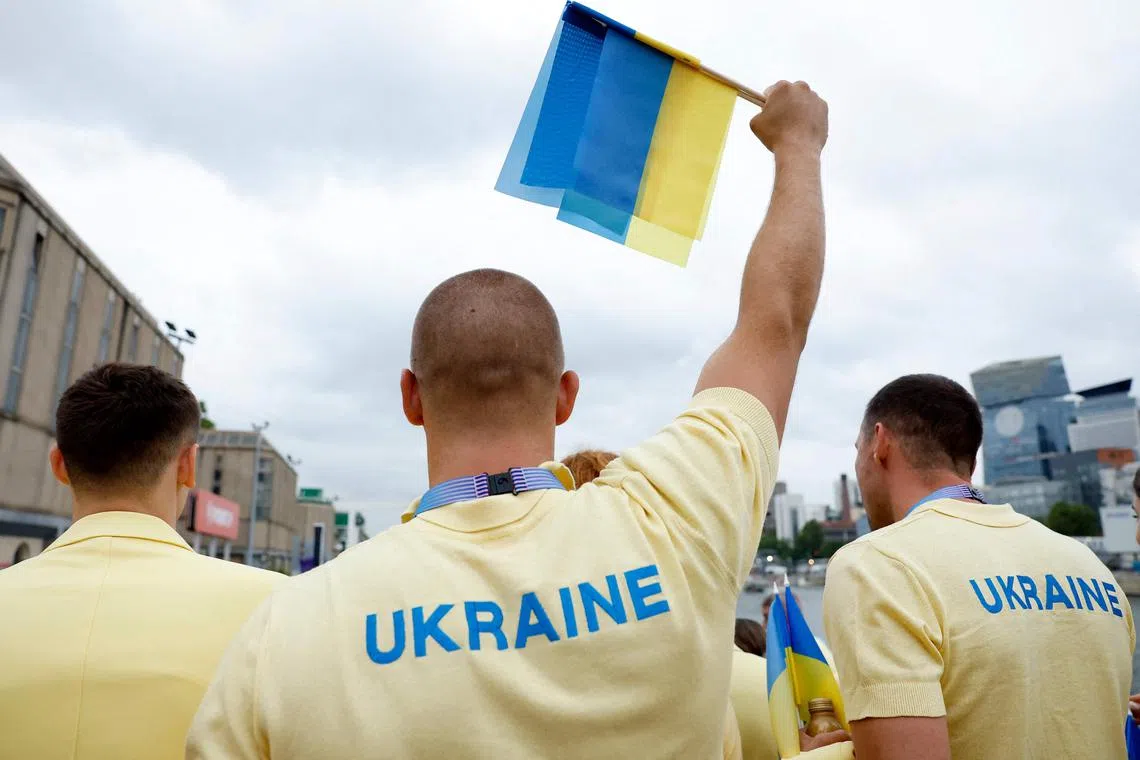 An athlete from Ukraine's delegation holding up a flag ahead of the Olympics opening ceremony on Paris' River Seine, on July 26.