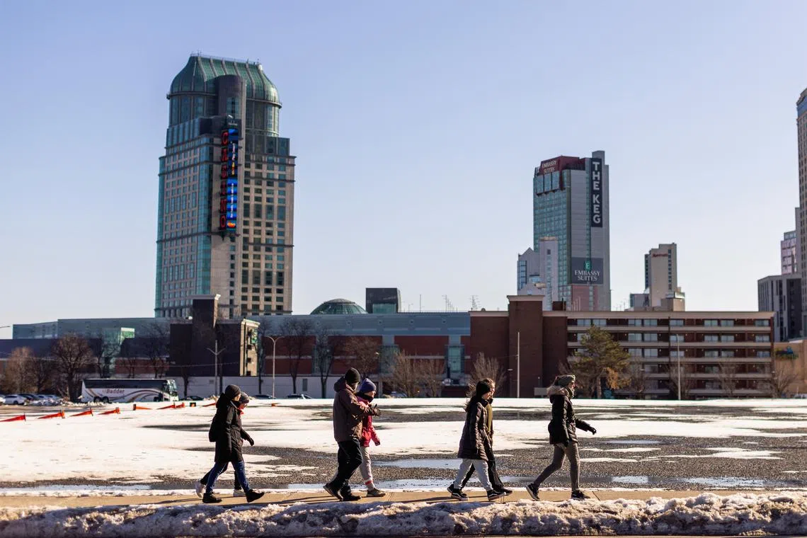 A group of people walk along a road, in Niagara Falls, Ontario, Canada March 7, 2023. REUTERS/Carlos Osorio