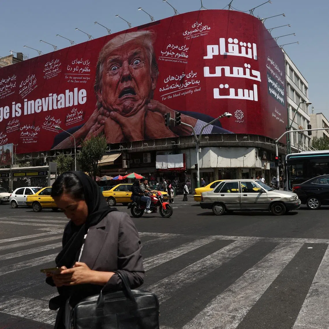 A woman walks near a billboard depicting U.S. President Donald Trump on a building in Tehran, Iran, July 27, 2026. Majid Asgaripour/WANA (West Asia News Agency) via REUTERS