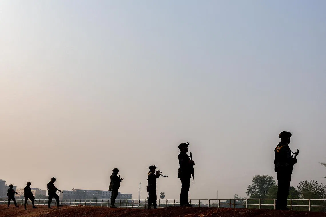 Soldiers stand guard as hundreds of refugees cross over the river frontier between Myanmar and Thailand.