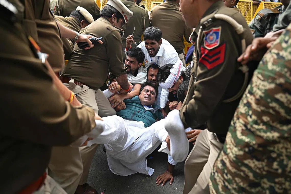 Police personnel detaining members of the Indian Youth Congress (IYC) during a protest against Indian industrialist Gautam Adani, in New Delhi on Nov 25, 2024. 