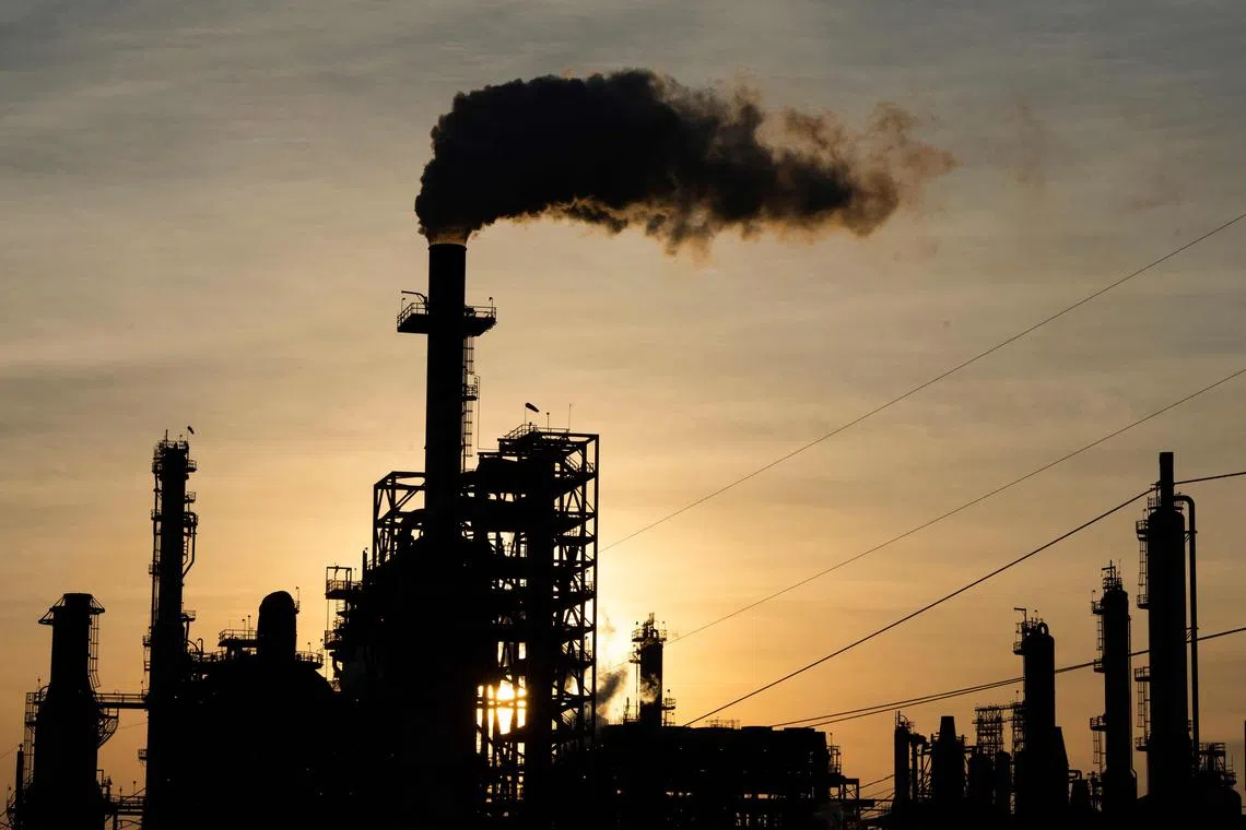 (FILES) The sun sets behind smoke rising from the LyondellBasell-Houston Refining plant in Houston, Texas, on April 20, 2020. An escalation of the war between Israel and Hamas could further strain global oil and gas supplies, already disrupted by Russia's invasion of Ukraine, experts warn. (Photo by Mark Felix / AFP)