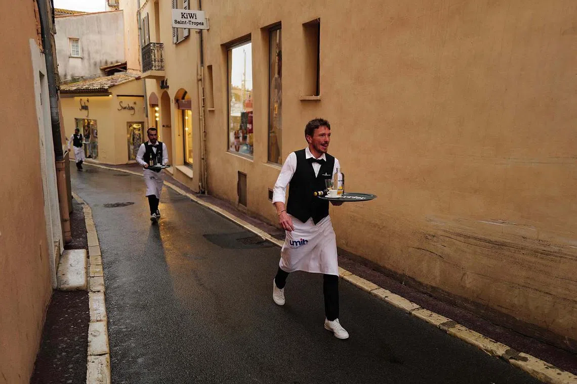 A waiter competing in the third edition of a cafe waiters race in Saint-Tropez, southeastern France, on April 27, 2025. 