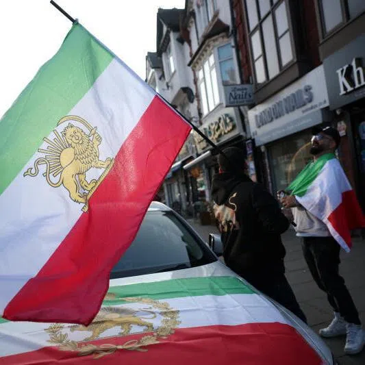 Iranian men hold pre-Iranian Revolution "Lion and Sun" flags in Finchley, an area home to a large Iranian community, in London, Britain.