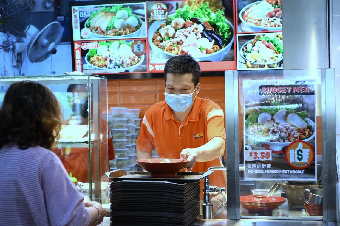 A hawker at a stall with the budget meal sticker serving up a bowl of teochew noodles.