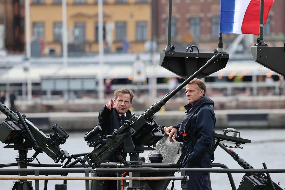 French President Emmanuel Macron (right) and Swedish Prime Minister Ulf Kristersson standing aboard a Swedish Navy CB90 fast assault craft in Stockholm, Sweden, on Aug 31.