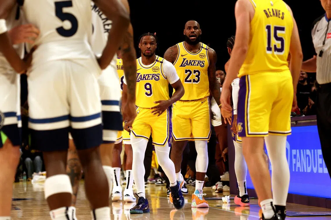 Oct 22, 2024; Los Angeles, California, USA; Los Angeles Lakers forward LeBron James (23) checks into the game with his son, guard Bronny James (9) during the second quarter against the Minnesota Timberwolves at Crypto.com Arena. This marked the first time in NBA history that a father and son played together. Mandatory Credit: Jason Parkhurst-Imagn Images