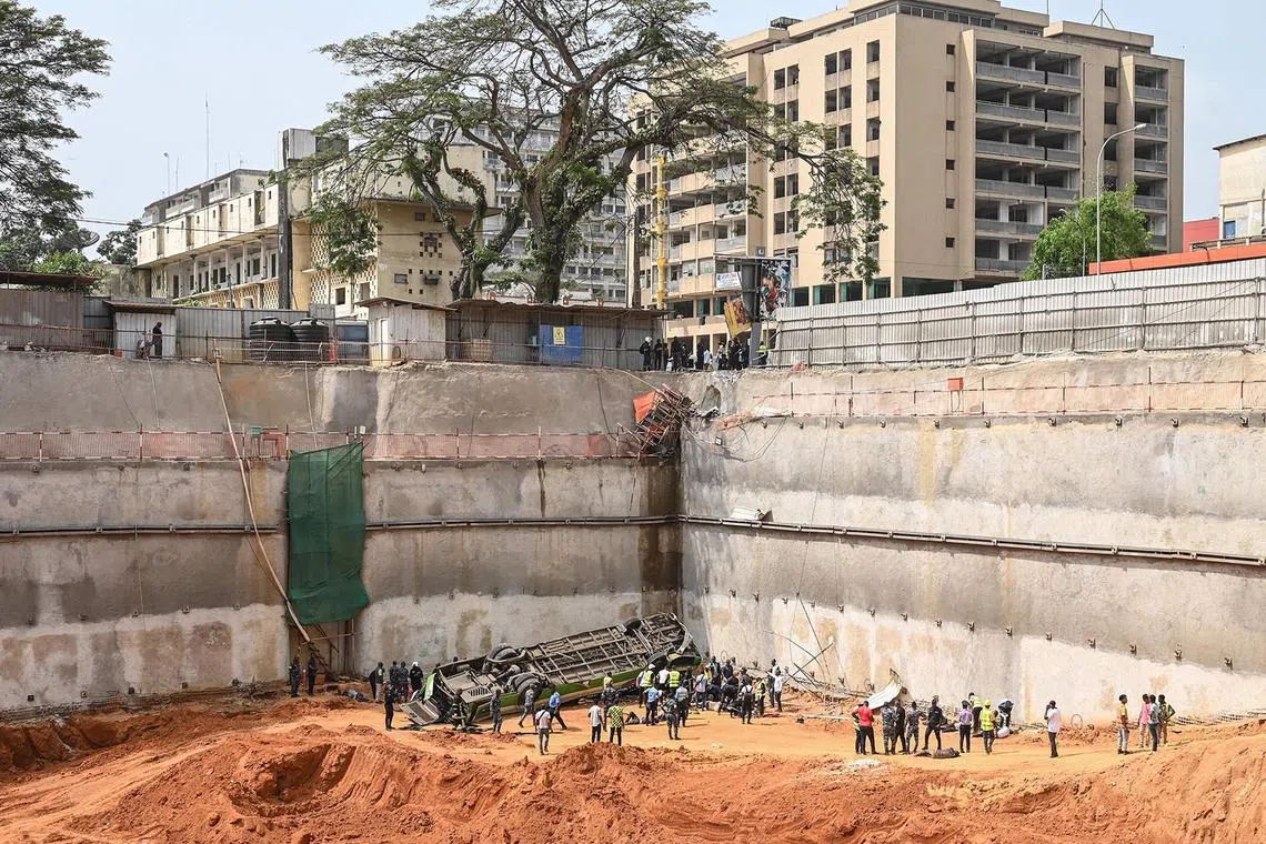 TOPSHOT - Several police officers and firefighters tend to injured passengers after an Abidjan Transport Company (SOTRA) bus fell into a construction site in the Plateau business district of Abidjan on December 26, 2024. (Photo by Sia KAMBOU / AFP)