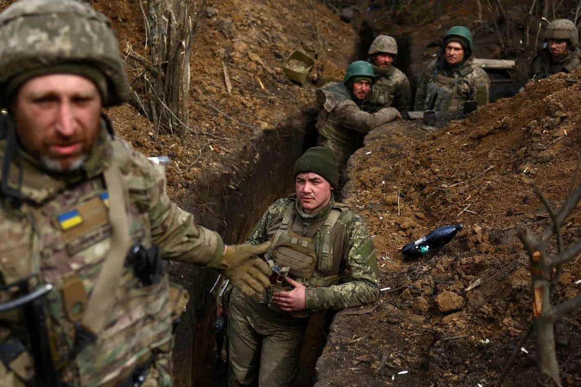 Ukrainian servicemen stay in their trenches amid incoming fire, near Bakhmut in Ukraine. 