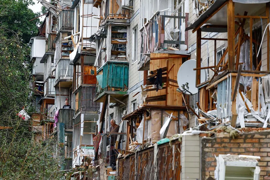 Residents standing on balconies of their apartment building damaged during Russian missile and drone strikes, amid Russia’s attack on Ukraine, in Kyiv, Ukraine July 31, 2025. 