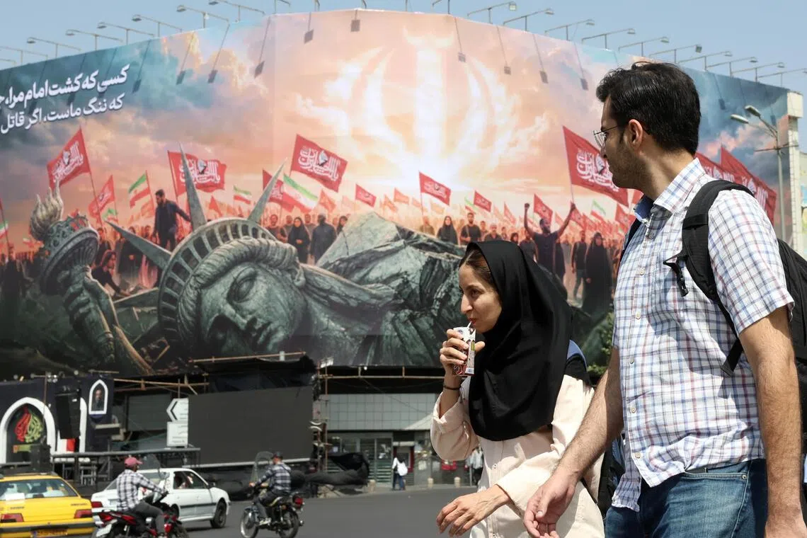 A couple walking past a large political billboard showing a toppled Statue of Liberty.