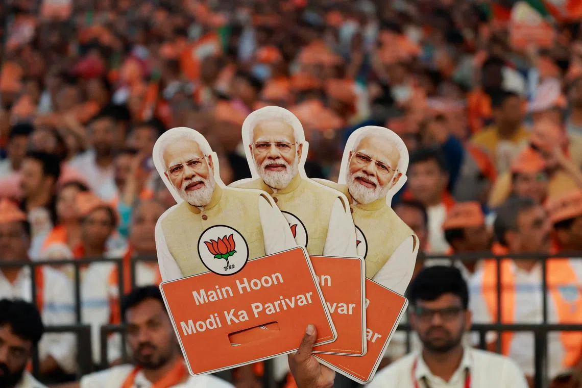 FILE PHOTO: A supporter of India's ruling Bharatiya Janata Party (BJP) holds cutouts of Prime Minister Narendra Modi during an election campaign where Modi speaks, in Bengaluru, Karnataka, India April 20, 2024. REUTERS/Navesh Chitrakar/File Photo