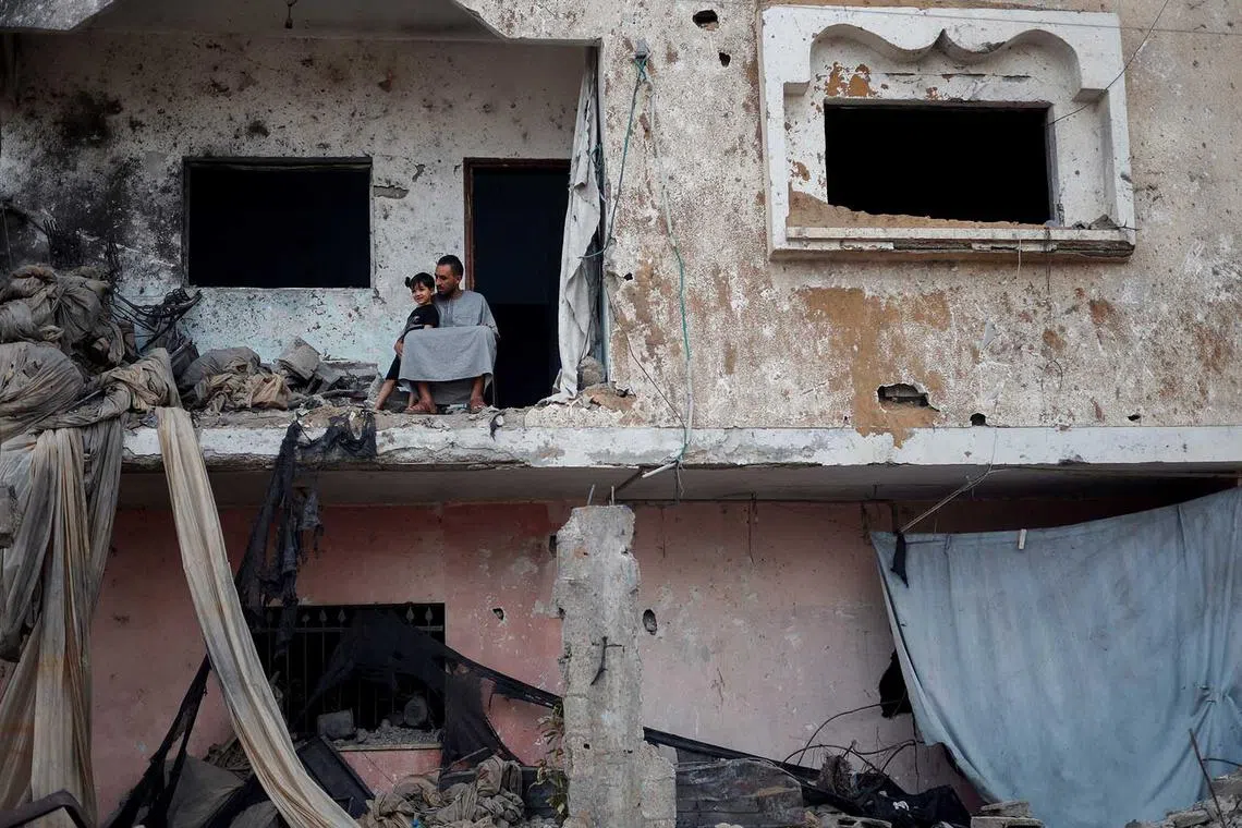 A Palestinian boy stands next to his father at their house, which was destroyed by Israeli air strikes during recent Israel-Gaza fighting, in Beit Lahiya, in the northern Gaza Strip, May 22, 2023. REUTERS/Mohammed Salem TPX IMAGES OF THE DAY