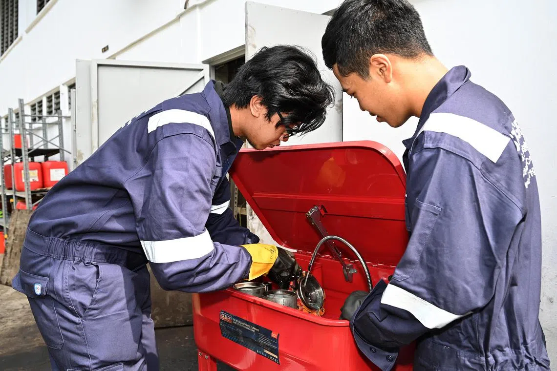 ITE students Hilman Azman and Muhammad Nor Aqil Kamis cleaning machinery parts inside the parts washer tank. 

PHOTO: ITE
