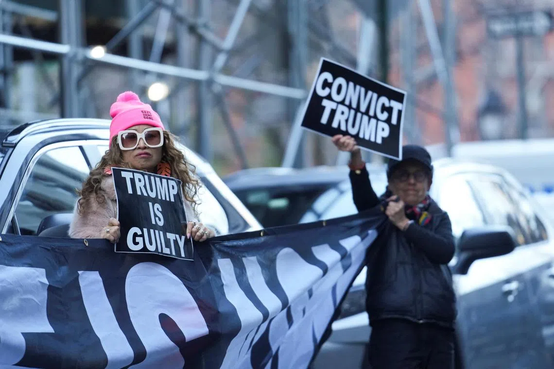 Anti-Trump protesters hold signs outside Manhattan Criminal Court after former US President Donald Trump's indictment, in New York City, on March 30, 2023. 