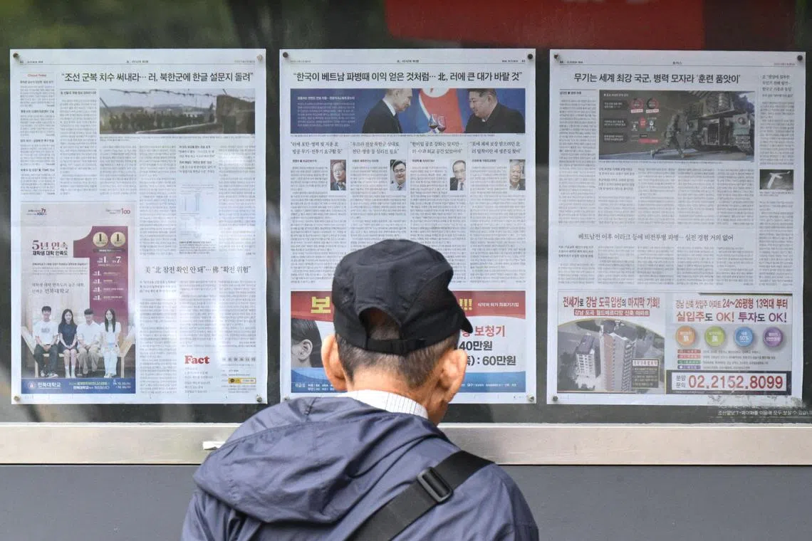 (FILES) A man walks past a newspaper displayed on a street for the public in Seoul on October 21, 2024, with coverage on North Korea's decision to deploy thousands of soldiers to Ukraine's front lines and a photo (C) of North Korean leader Kim Jong Un and Russia's President Vladimir Putin toasting at a banquet in Pyongyang earlier this year. North Korea has sent 1,500 more soldiers to Russia, Seoul's spy agency told lawmakers on October 23, 2024, with 10,000 troops expected to be deployed by December. (Photo by Anthony WALLACE / AFP)