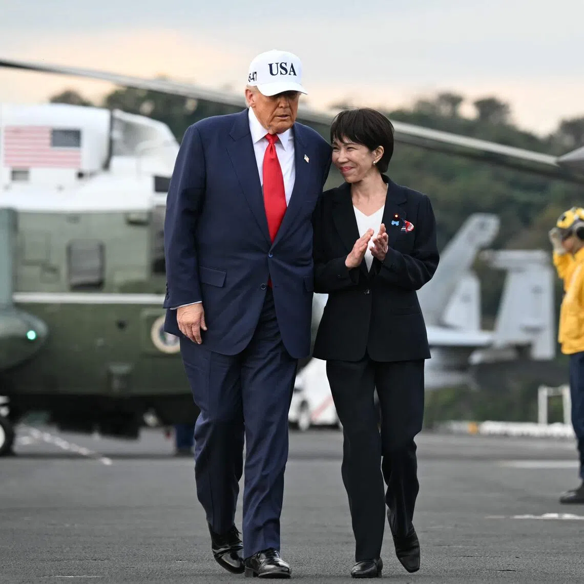 US President Donald Trump (L) and Japan's Prime Minister Sanae Takaichi (2nd L) walk past rainbow sideboys in salute on board the USS George Washington aircraft carrier at the US naval base in Yokosuka, Japan, on October 28.