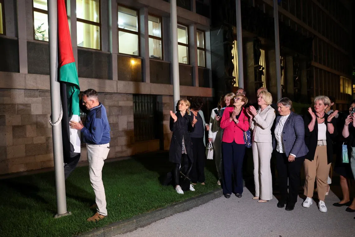 A man puts up the flag of Palestine as members of parliament applaud after the Slovenian parliament approved the recognition of an independent Palestinian state, in Lubljana, Slovenia June 4, 2024. REUTERS/Borut Zivulovic