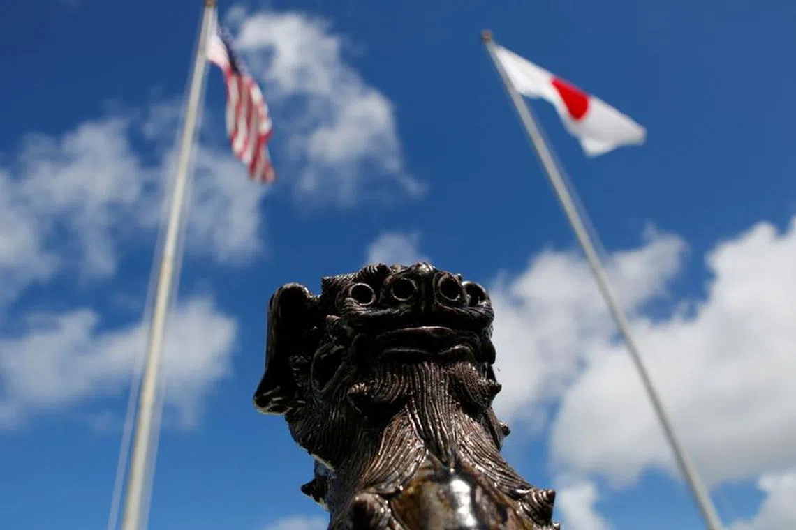 The U.S. (L) and Japanese national flags are hoisted next to a traditional Okinawan Shisa statue at the U.S. Marine's Camp Foster in Ginowan, on the southern island of Okinawa, Japan June 18, 2016. REUTERS/Tim Kelly/file photo