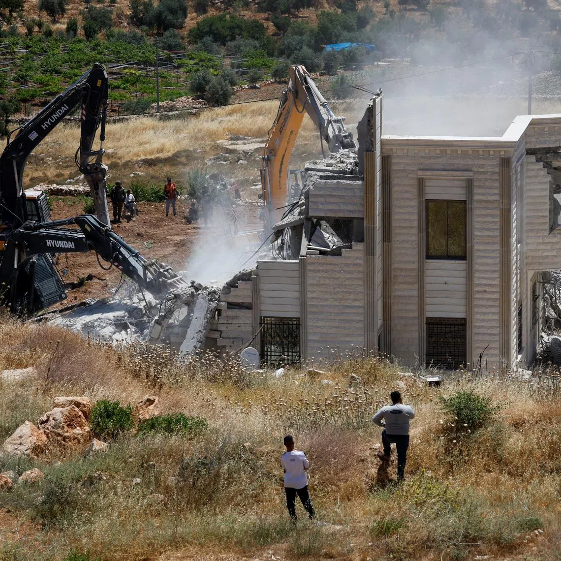 Palestinians observe, as heavy machinery demolishes a Palestinian house near Hebron, in the Israeli-occupied West Bank, June 8, 2026. REUTERS/Mussa Qawasma