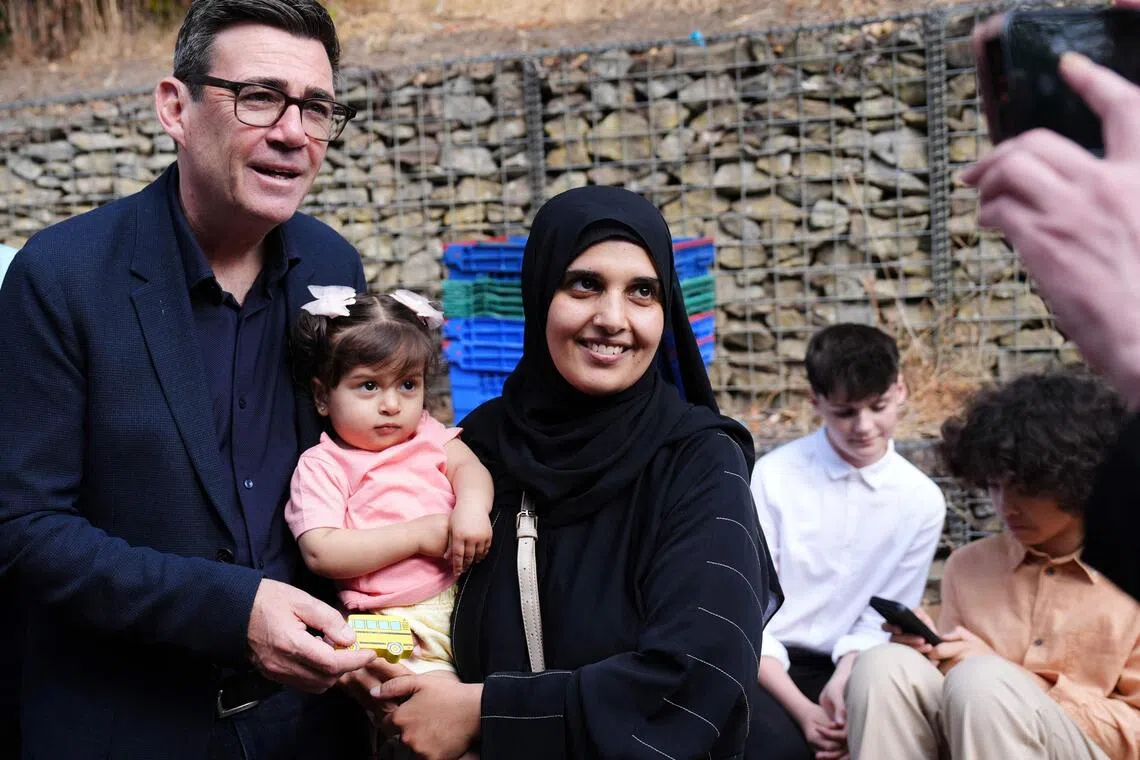 Britain’s Prime Minister Andy Burnham with a mother and child during a visit to a family centre in Sheffield, northern England, on July 31.