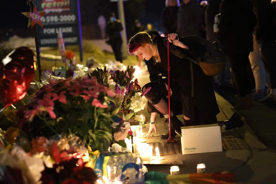 People hold a vigil at a makeshift memorial near the Club Q nightclub in Colorado Springs after the mass shooting. 