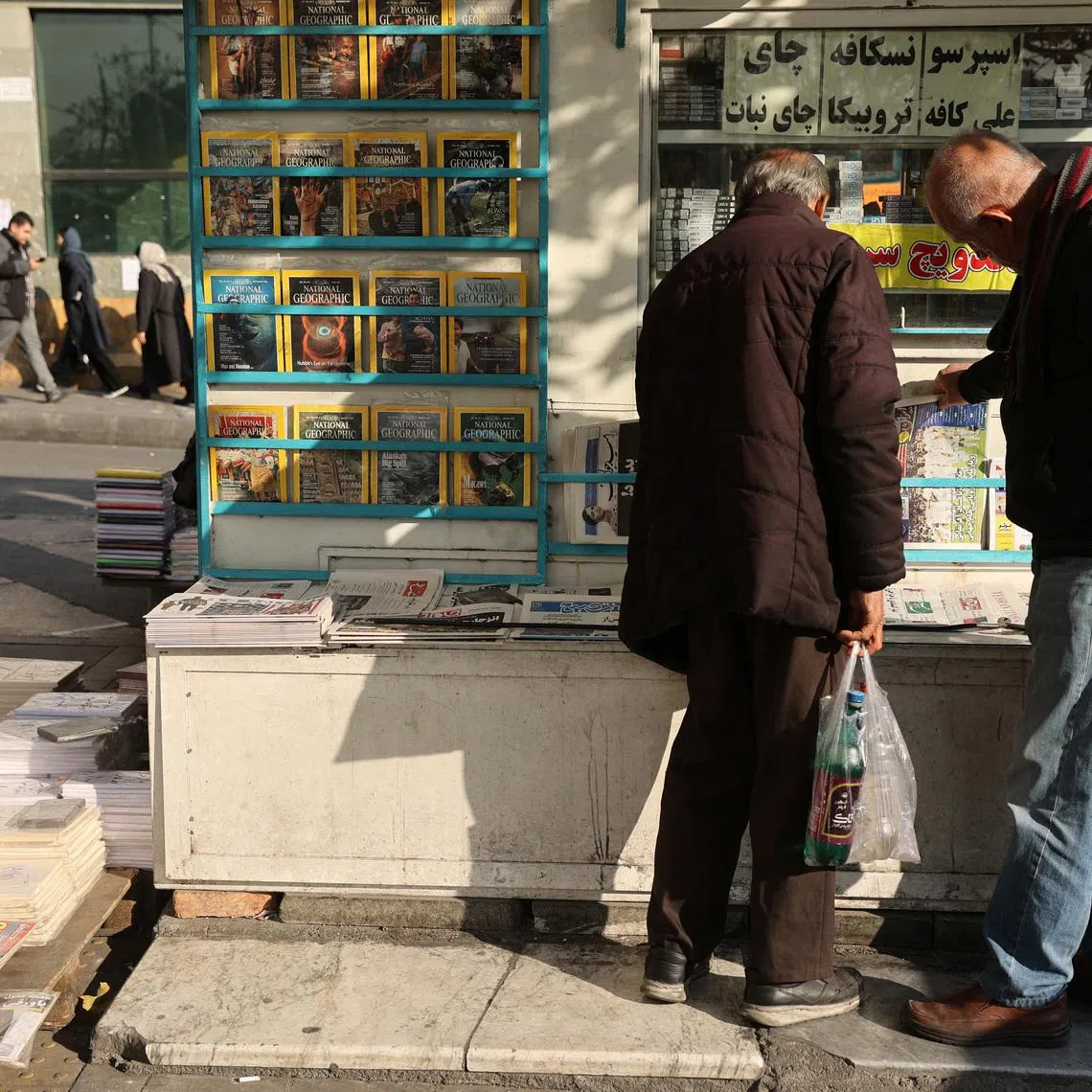 Iranian men read newspapers on a street, as protests erupt over the collapse of the currency's value, in Tehran, Iran, January 5, 2026. Majid Asgaripour/WANA (West Asia News Agency) via REUTERS
