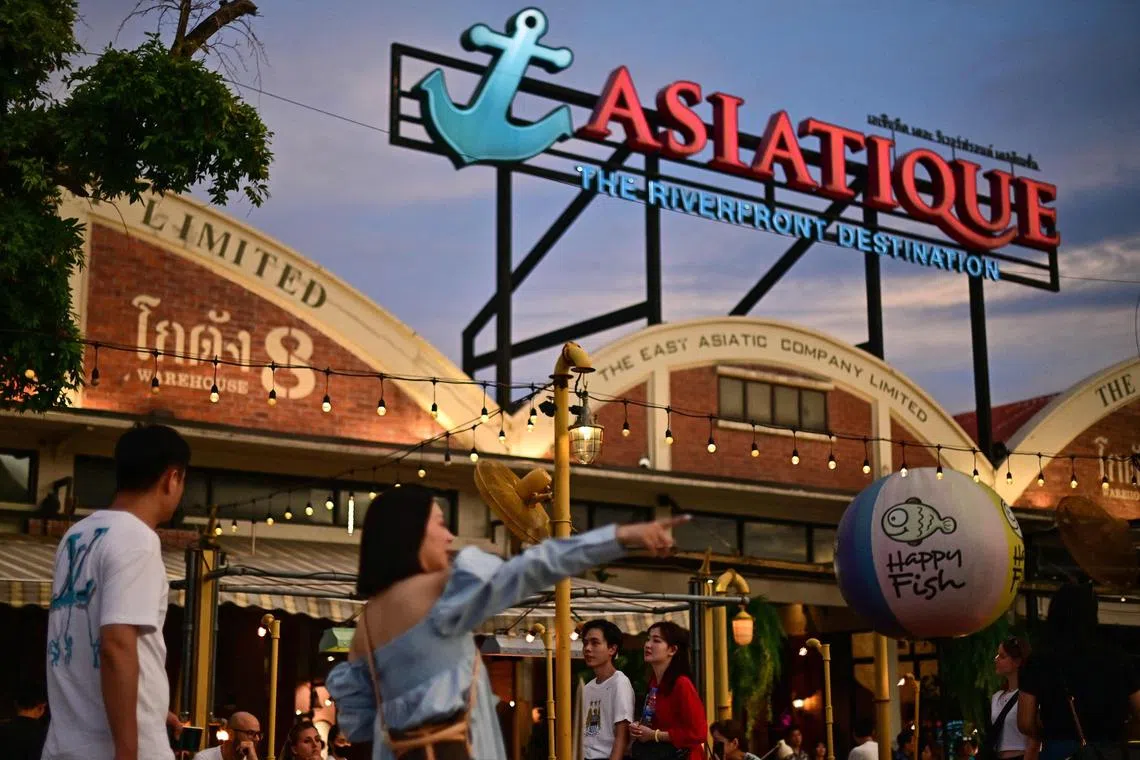 Tourists walk along the Asiatique Riverfront along the Chao Phraya river in Bangkok on June 11, 2023. (Photo by MANAN VATSYAYANA / AFP)