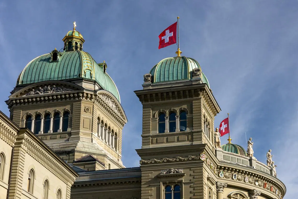 FILE PHOTO: Swiss flags flutter on the Swiss Parliament Building (Bundeshaus), after the weekly governmental meeting in Bern, Switzerland, January 29, 2025. REUTERS/Denis Balibouse/File Photo