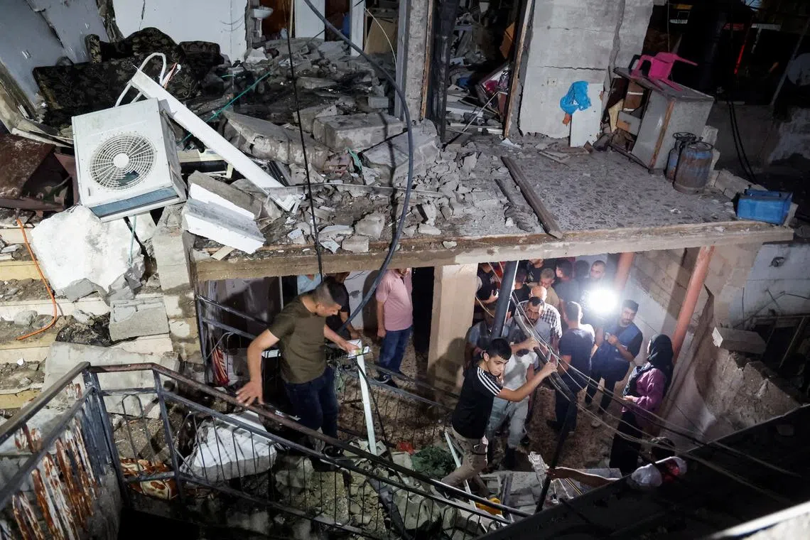 People walk in a damaged building targeted by Israeli forces during a raid in which Palestinians were killed, in Kafr Dan, near Jenin, in the Israeli-occupied West Bank June 11, 2024. REUTERS/Raneen Sawafta