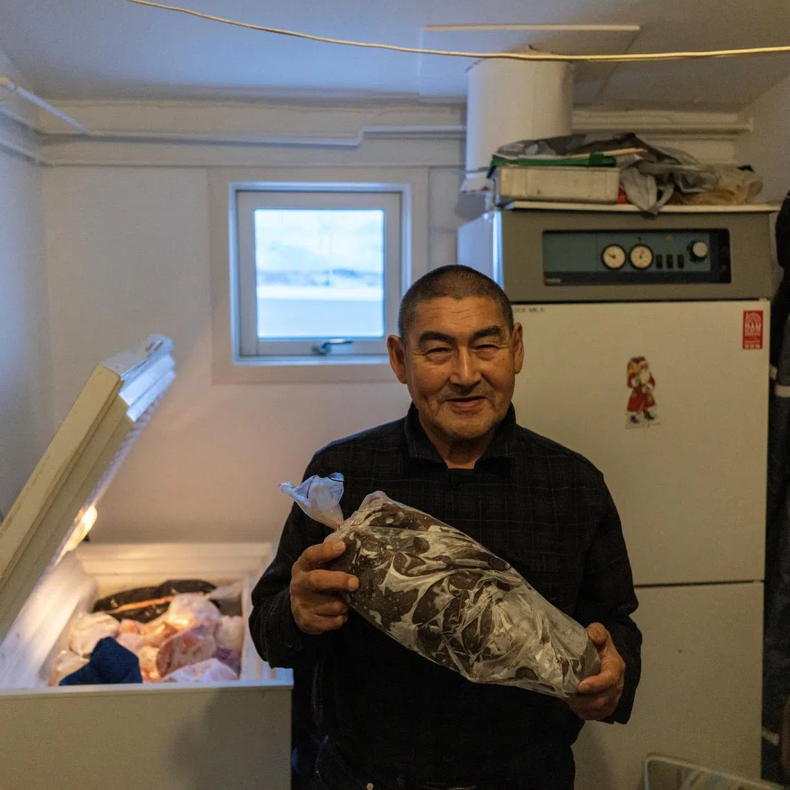 Kaaleeraq Ringsted, 74, poses with his frozen food in his home in Kapisillit, Greenland, January 21, 2026. REUTERS/Marko Djurica